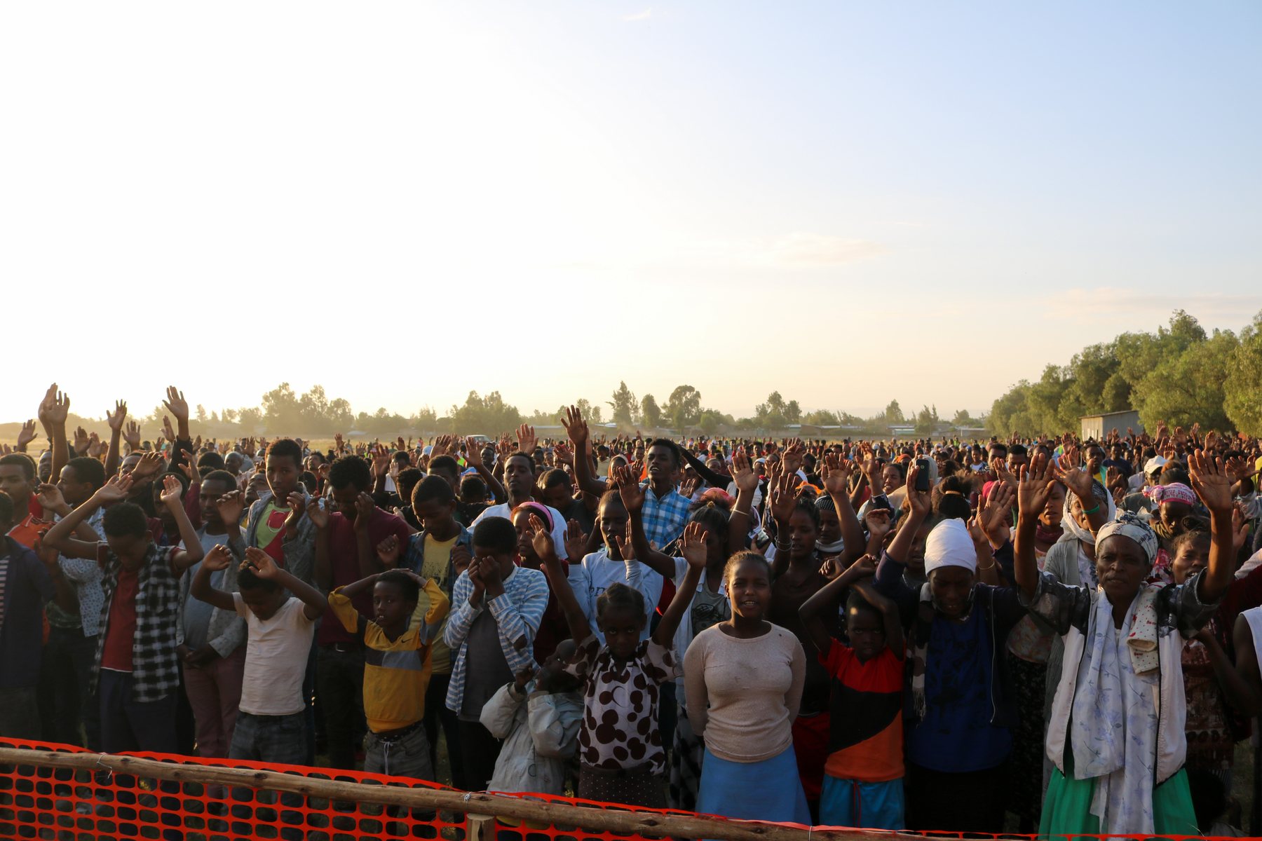 Open-air crowd responding in prayer