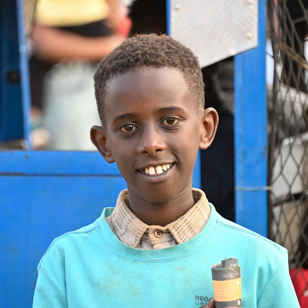 Smiling boy beside a blue vehicle